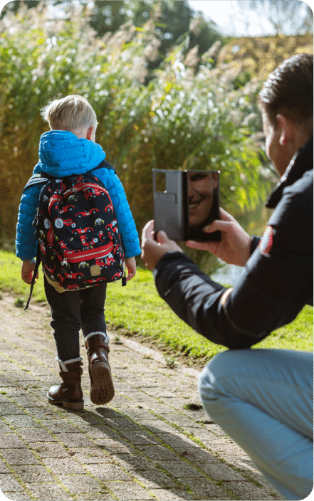Ein Elternteil fotografiert ein Kind mit seinem Rucksack